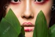 Schönes asiatisches Mädchen mit einem hellen Make-up-Kunst in grünen  Blättern. Beauty