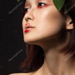 Beautiful Asian girl with a bright make-up art in green leaves. Beauty  face. Creative image. Picture taken in the studio. — Foto von kobrin-photo