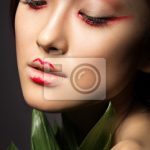 Fototapete Schöne asiatische Mädchen mit einem hellen Make-up-Kunst in  grünen Blättern.