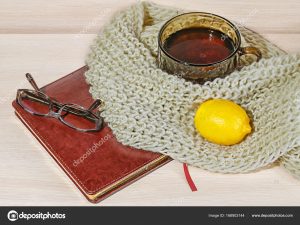 Gemütlich und weich Winter Hintergrund. Tasse Tee mit Zitrone und warme  gestrickte Pullover oder eine Decke auf Urlaub zu Hause Vintage Holzbrett.